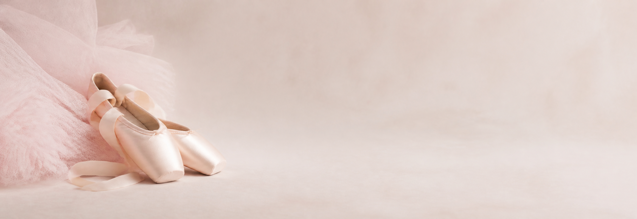 Zapatillas de punta junto a un tutú de ballet rosa